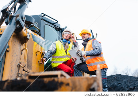 Woman and man worker in quarry on excavation machine 62652900
