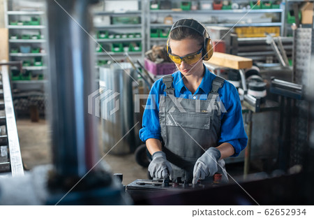 Woman worker operating a machine tool in metal workshop or factory Woman worker operating a machine tool in metal workshop or factory 62652934
