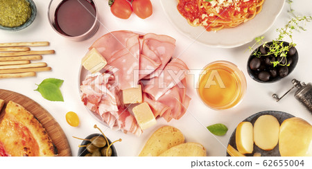 Italian cold cuts overhead panoramic shot. An assortment of hams and cheeses, shot from the top on a white background with wine 62655004