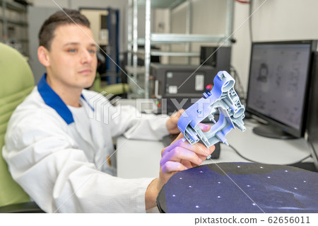 Quality engineer examines a sample scanned with a laser on a 3d scan in a research laboratory 62656011