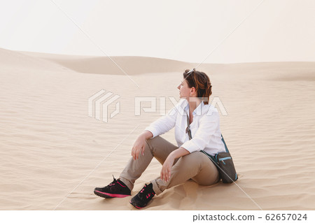 Calm woman sitting on sand 62657024