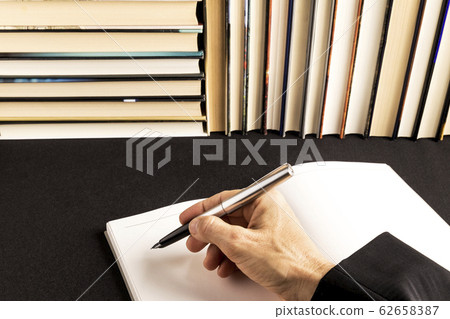 woman writing in a blank book beside a book woman writing in a blank book beside a book 62658387