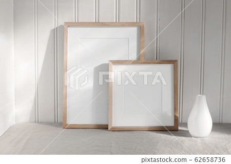 Two portrait and square wooden frame mockups. Linen cloth and modern ceramic vase with in sunlight. White beadboard wainscot wall paneling background. Scandinavian interior, home design. Art concept. Two portrait and square wooden frame mockups. Linen cloth and modern ceramic vase with in sunlight. White beadboard wainscot wall paneling background. Scandinavian interior, home design. Art concept. 62658736