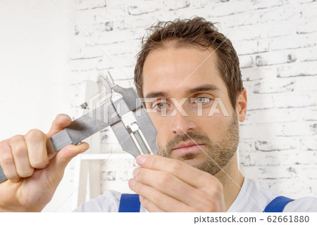 young man measuring screw using caliper 62661880