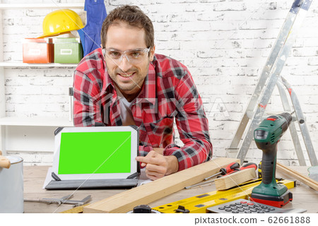 smiling young carpenter showing green screen on smiling young carpenter showing green screen on 62661888