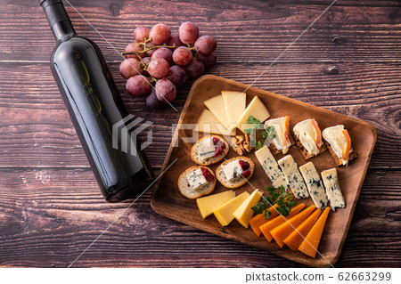 Assorted cheeses of various types and red wine Assorted cheeses of various types and red wine 62663299