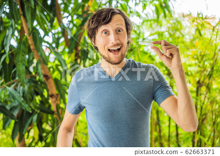 Man placing a bite plate in his mouth to protect his teeth at night from grinding caused by bruxism Man placing a bite plate in his mouth to protect his teeth at night from grinding caused by bruxism 62663371
