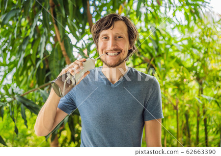 Young man uses an oral irrigator to brush his teeth Young man uses an oral irrigator to brush his teeth 62663390