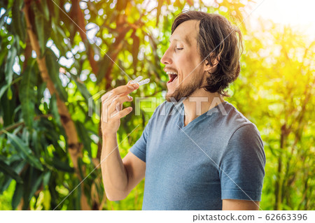 Man placing a bite plate in his mouth to protect his teeth at night from grinding caused by bruxism 62663396