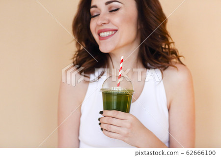 Delighted female with green smoothie laughing Delighted female with green smoothie laughing 62666100
