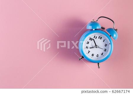 Blue vintage alarm clock on light pink color Blue vintage alarm clock on light pink color 62667174