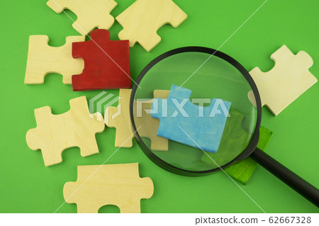 Jigsaw puzzle pieces with magnifying glass Jigsaw puzzle pieces with magnifying glass 62667328