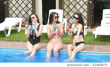 Woman's body with cocktail glass near swimming pool 62668673