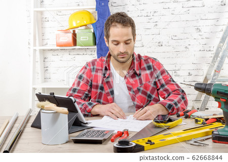 smiling carpenter sitting at the desk, in his smiling carpenter sitting at the desk, in his 62668844