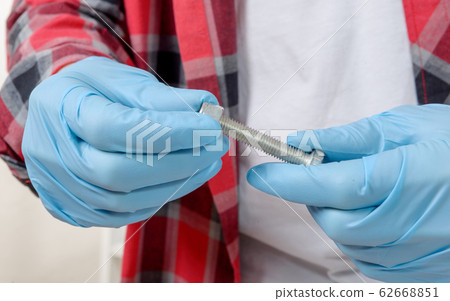 close-up hands of a technician screwing a bolt 62668851