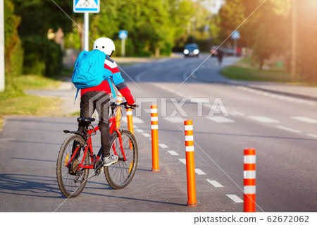 Child with rucksack riding on bike in the park near school Child with rucksack riding on bike in the park near school 62672062