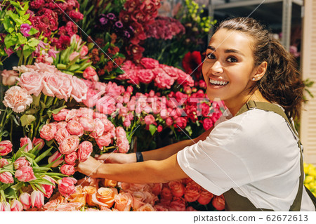 Beautiful florist woman looking at camera in front of a bouquets of flowers Beautiful florist woman looking at camera in front of a bouquets of flowers 62672613