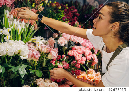 Florist woman choosing a flower in her shop Florist woman choosing a flower in her shop 62672615