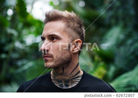 Front view of young man standing in botanical garden. 62672807