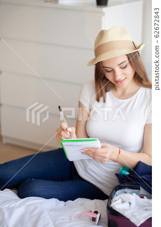 Beautiful woman collects clothes in travel suitcase on a trip Beautiful woman collects clothes in travel suitcase on a trip 62672843