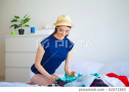 Beautiful woman collects clothes in travel suitcase on a trip Beautiful woman collects clothes in travel suitcase on a trip 62672865