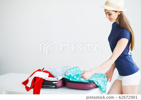 Beautiful woman collects clothes in travel suitcase on a trip Beautiful woman collects clothes in travel suitcase on a trip 62672901