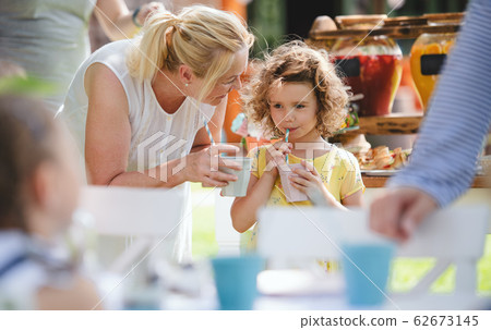 Grandmother and small girl outdoors on garden party in summer, drinking. Grandmother and small girl outdoors on garden party in summer, drinking. 62673145
