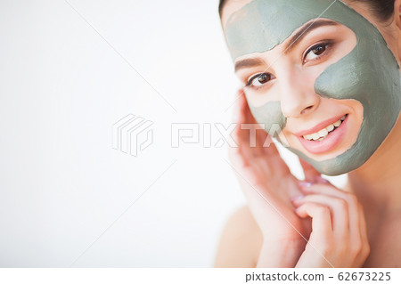 Skin Care. Young Woman With Cosmetic Clay Mask Holding Cucumber At Her Bathroom 62673225