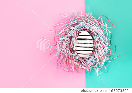 Graphic hand-painted line egg in decorative nest on pastel background. Graphic hand-painted line egg in decorative nest on pastel background. 62673831