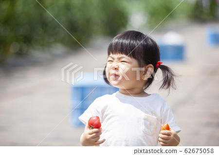 Girls eating tomatoes 62675058