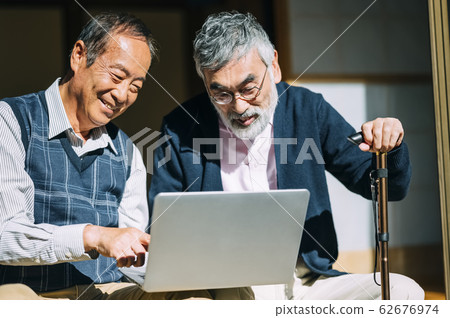 Senior man and his friend looking at personal computer Senior man and his friend looking at personal computer 62676974