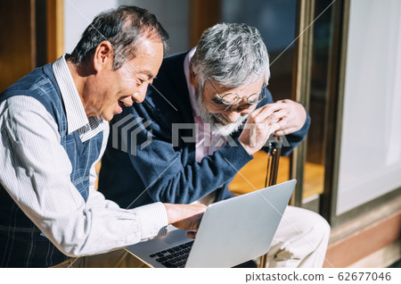 Senior man and his friend looking at personal computer Senior man and his friend looking at personal computer 62677046