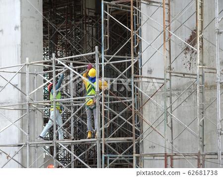 Construction workers working at height at the construction site. They are requested to wear appropriate safety gear to prevent bad happen to them.  62681738