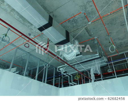 Air condition duct and other services above ceiling level coordinated and installed by construction workers  at the construction site  62682456