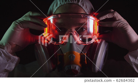 Man in protective costume suit, gas protect medical spray paint mask. Doctor in respirator. Concept health virus coronavirus epidemic. Man in protective costume suit, gas protect medical spray paint mask. Doctor in respirator. Concept health virus coronavirus epidemic. 62684302