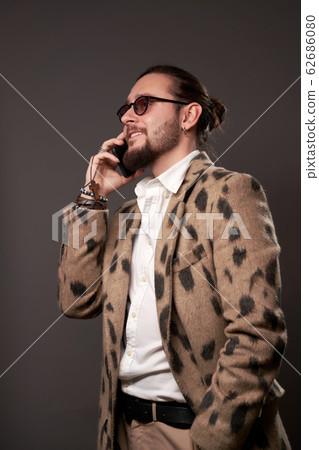 Male in sunglasses in jacket talking on phone on brown background 62686080