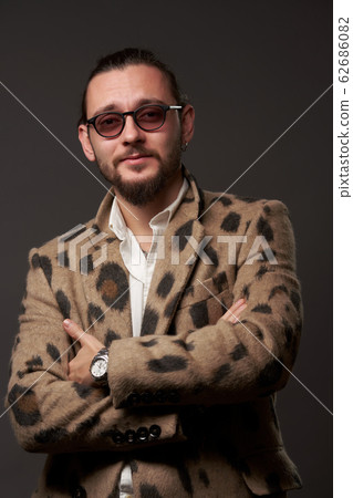 Male in sunglasses in jacket with arms crossed on brown background 62686082