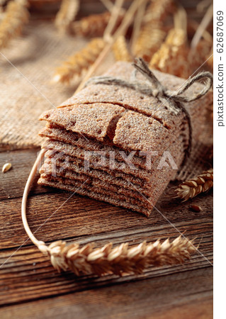 Rye crackers and ears on a wooden table. Rye crackers and ears on a wooden table. 62687069