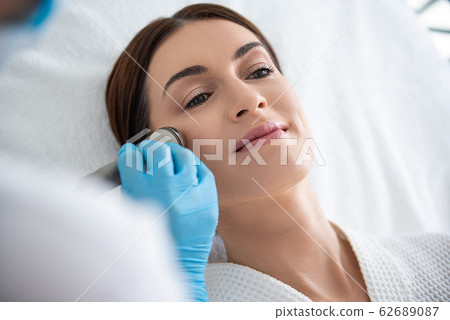 Pretty lady on face roll massage procedure Pretty lady on face roll massage procedure 62689087