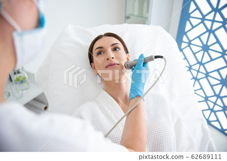 Lady enjoying of face roll massage procedure Lady enjoying of face roll massage procedure 62689111