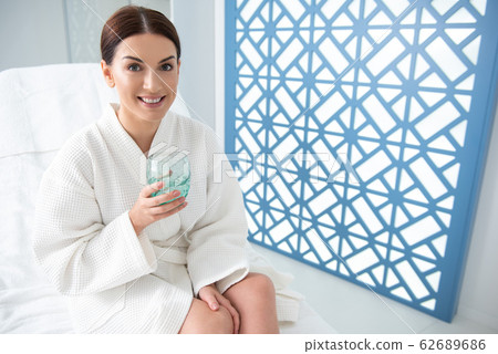 Happy female with glass of water on couch 62689686