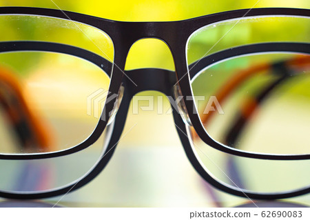 Two black shortsighted or nearsighted eyeglasses on white acrylic table, Bokeh green garden background, Close up & Macro shot, Selective focus, Reflection, Optical concept 62690083