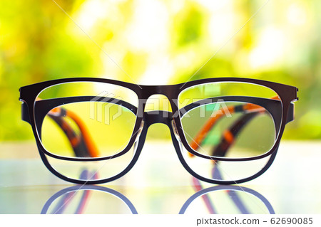 Two black shortsighted or nearsighted eyeglasses on white acrylic table, Bokeh green garden background, Close up & Macro shot, Selective focus, Reflection, Optical concept Two black shortsighted or nearsighted eyeglasses on white acrylic table, Bokeh green garden background, Close up & Macro shot, Selective focus, Reflection, Optical concept 62690085