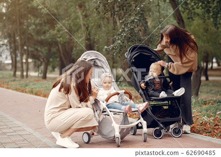 Two young mothers walking in a autumn park with carriages Two young mothers walking in a autumn park with carriages 62690485