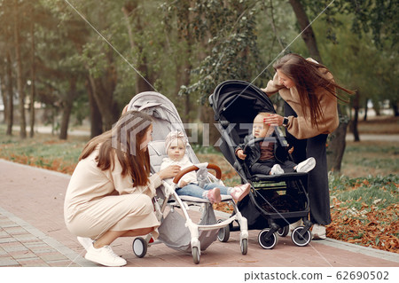 Two young mothers walking in a autumn park with carriages Two young mothers walking in a autumn park with carriages 62690502