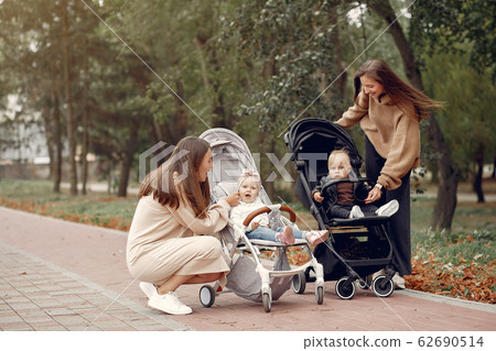 Two young mothers walking in a autumn park with carriages Two young mothers walking in a autumn park with carriages 62690514