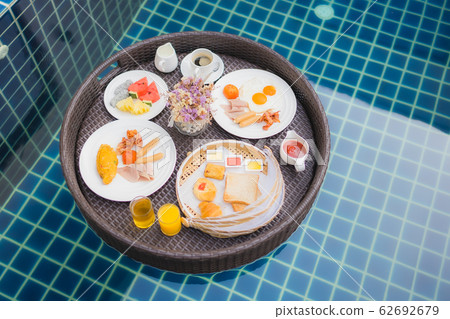 Breakfast set floating around swimming pool 62692679