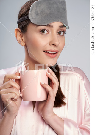 Charming lady with morning beverage standing against light blue background Charming lady with morning beverage standing against light blue background 62693185