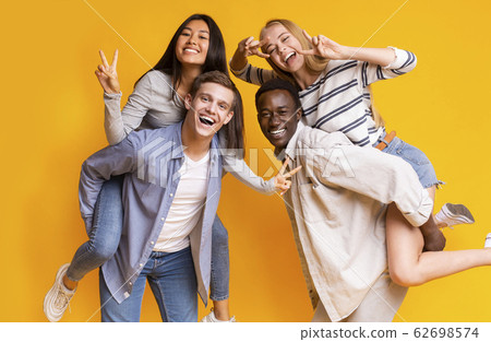Two international teen couples having fun over yellow background 62698574