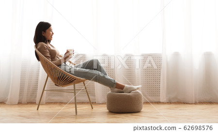 Full relaxation. Girl sitting in armchair and enjoying coffee Full relaxation. Girl sitting in armchair and enjoying coffee 62698576